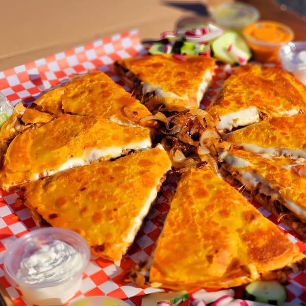 Golden-brown quesadillas, cut into wedges, filled with melted cheese and caramelized onions, served with dipping sauces.