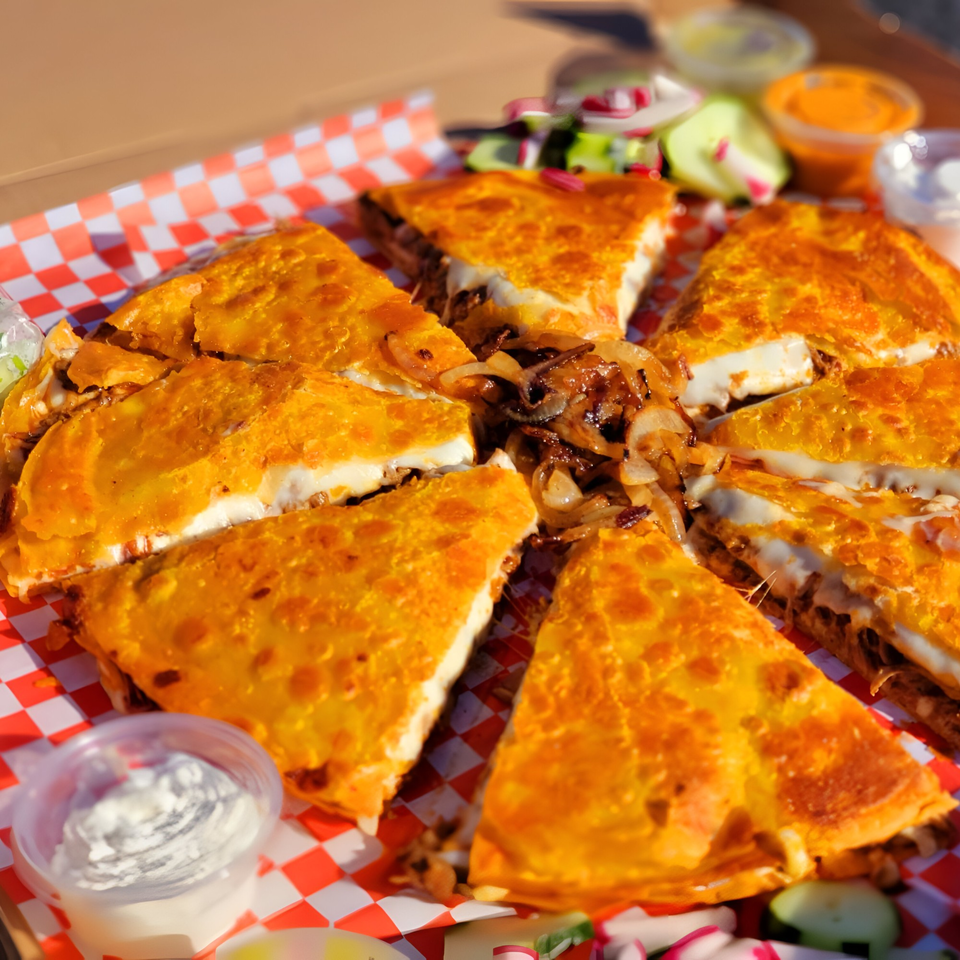 Golden-brown quesadillas, cut into wedges, filled with melted cheese and caramelized onions, served with dipping sauces.