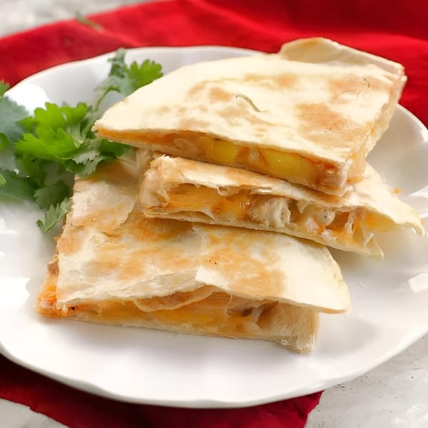 Stacked Mexican quesadilla wedges filled with melted cheese and corn, garnished with fresh cilantro.