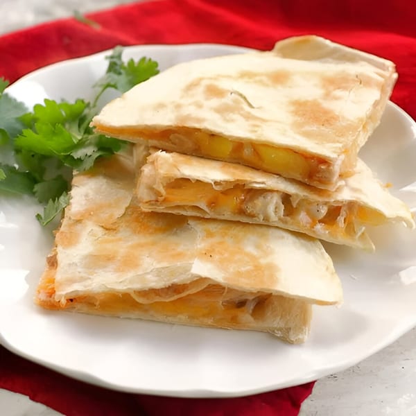 A stack of golden-brown quesadilla wedges filled with melted cheese and corn, garnished with cilantro.