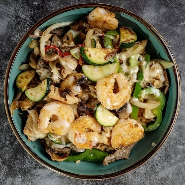Shrimp fajita bowl with zucchini, onions, bell peppers, and mushrooms in a teal bowl.